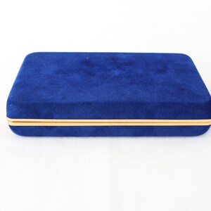 May include: A blue velvet jewelry box with a gold trim.