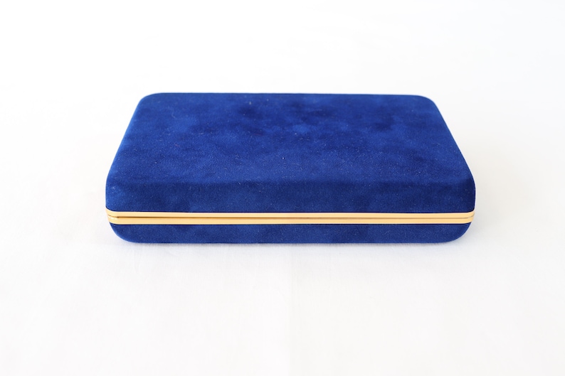 May include: A blue velvet jewelry box with a gold trim.