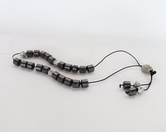 May include: A black hematite beaded necklace with silver accents and a silver clasp. The beads are cylindrical and have a smooth, polished finish.