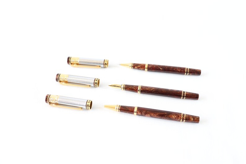 May include: Four pens, two with silver and gold accents and two with brown wood-like accents. The pens with silver and gold accents are disassembled, showing the inner workings of the pen.
