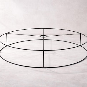 May include: A black metal lampshade frame, circular in shape, with a central ring and vertical supports. The frame is made of thin metal rods and is designed to hold a lampshade. The design is minimalist and modern.