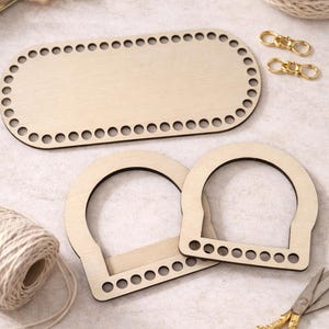 May include: Wooden basket bases and handles, perfect for crafting. The set includes an oval base, two arched handles, gold-colored clasps, scissors, and twine. The natural wood pieces have pre-drilled holes for easy assembly. A crafting project.