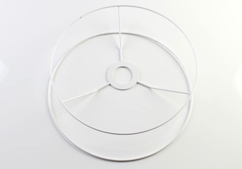 Puede incluir: Estructura de pantalla de l&aacute;mpara de metal blanco con base circular y tres alambres de soporte.