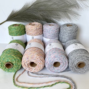 Könnte beinhalten: Fünf Spulen Baumwollkordel in verschiedenen Farben, darunter Grün, Rosa, Grau und Blau. Die Spulen sind mit "Cotton Cord" beschriftet.