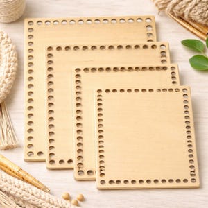 May include: Four square wooden basket bases in varying sizes. Each base is light-colored with a series of evenly spaced holes around the perimeter. The bases are stacked, showcasing their different dimensions and the potential for crafting.