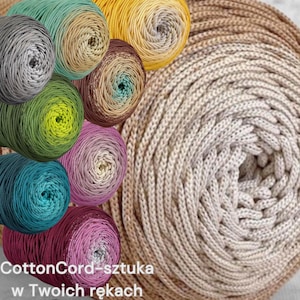 Könnte beinhalten: Eine Sammlung farbiger Garnknäuel in verschiedenen Farbtönen, darunter Türkis, Gelb und Rosa, mit einem großen, aufgerollten beigefarbenen Garn im Hintergrund. Der Text "CottonCord-sztuka w Twoich rękach" ist unten sichtbar.