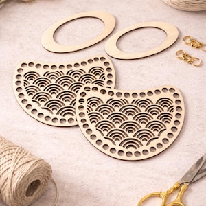May include: Wooden craft supplies including two oval-shaped pieces, two semi-circular pieces with a wave pattern, gold-colored scissors, and gold-colored clasps. The items are arranged on a light-colored surface, suggesting a crafting theme.