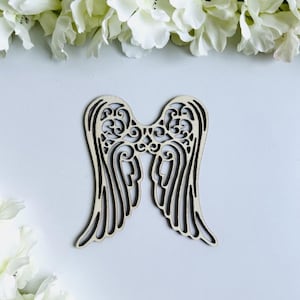 Op de afbeelding: Houten engelenvleugels met een decoratief, ingewikkeld ontwerp. De vleugels zijn lichtbruin en hebben een uitgesneden patroon.