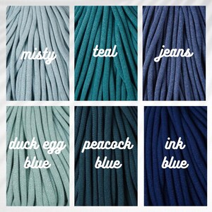 May include: Close-up of six bundles of thick, soft, colored yarn. Colors include misty, teal, jeans, duck egg blue, peacock blue, and ink blue. Each bundle has a handwritten label with the color name.