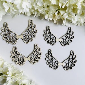 Op de afbeelding: Vier houten engelenvleugels met een delicaat, ingewikkeld ontwerp. De vleugels zijn gemaakt van natuurlijk hout en hebben een lichtbruine kleur.