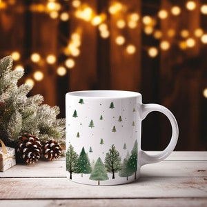 Könnte beinhalten: Weiße Keramik-Tasse mit einem Aquarelldesign aus grünen Weihnachtsbäumen und goldenen Punkten. Die Bäume variieren in Größe und Stil, einige haben weiße Akzente. Die Tasse hat einen gebogenen Henkel und steht vor einem verschwommenen Hintergrund mit Weihnachtsbeleuchtung.