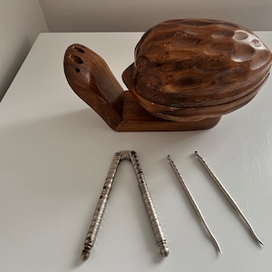 Könnte beinhalten: Ein Nussknacker aus Holz in Form einer Walnuss mit einem separaten Nussknackerwerkzeug und zwei Nusszangen.