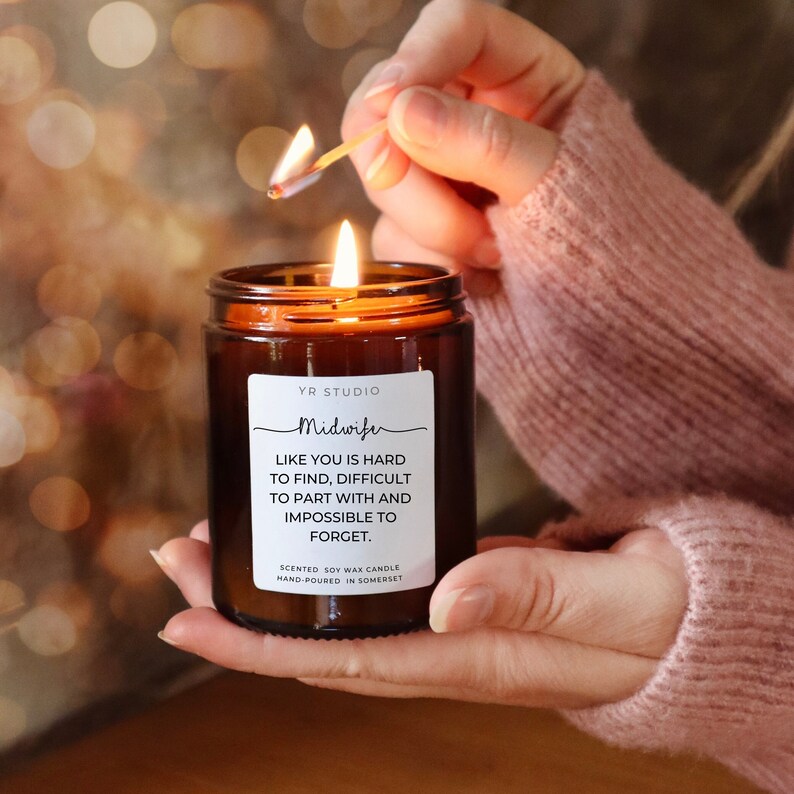 K&ouml;nnte beinhalten: Eine braune Glaskerze mit einem wei&szlig;en Etikett, auf dem steht: "YR STUDIO Midwife LIKE YOU IS HARD TO FIND, DIFFICULT TO PART WITH AND IMPOSSIBLE TO FORGET. SCENTED SOY WAX CANDLE HAND-POURED IN SOMERSET"