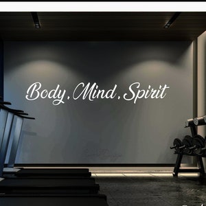 May include: A modern gym interior with treadmills and weight equipment. The wall has the text "Body. Mind. Spirit" written in white cursive font.