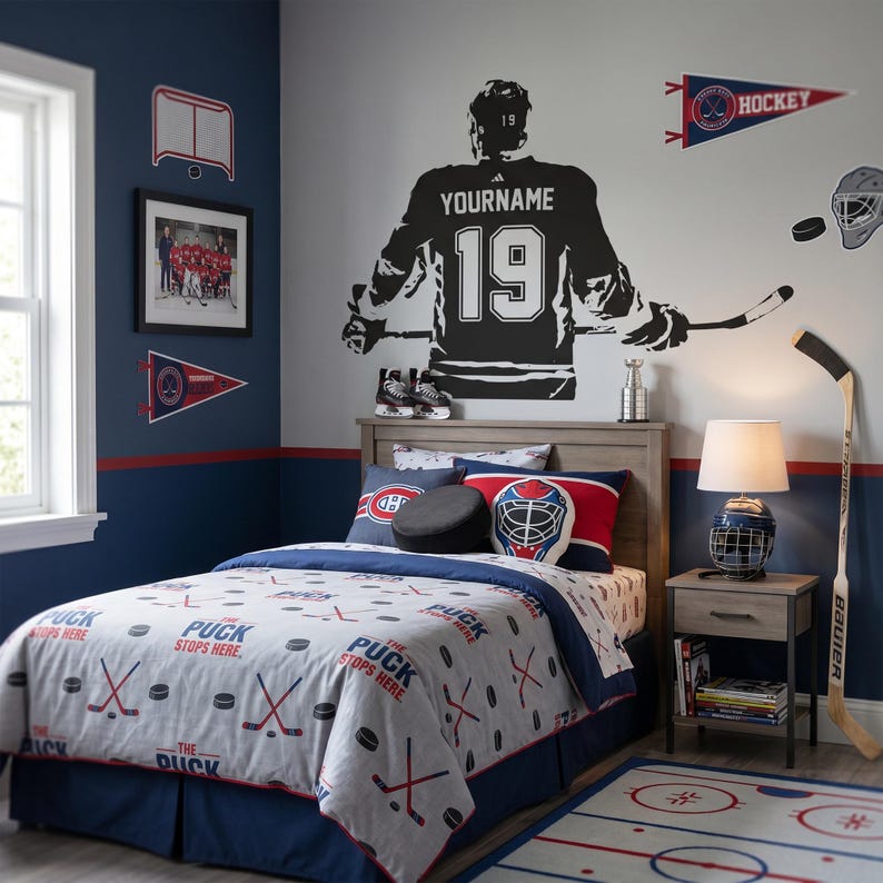 May include: A hockey-themed bedroom with a bed featuring a comforter and pillows with hockey puck and stick designs. A large black hockey player silhouette is on the wall, along with hockey-related wall decor, a hockey stick, and a rug.