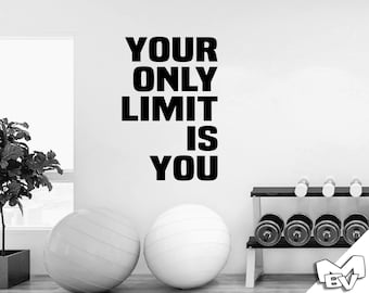 May include: Black and white motivational quote on a white wall that reads "Your Only Limit Is You". There are two white exercise balls and a weight rack with black weights in the foreground.