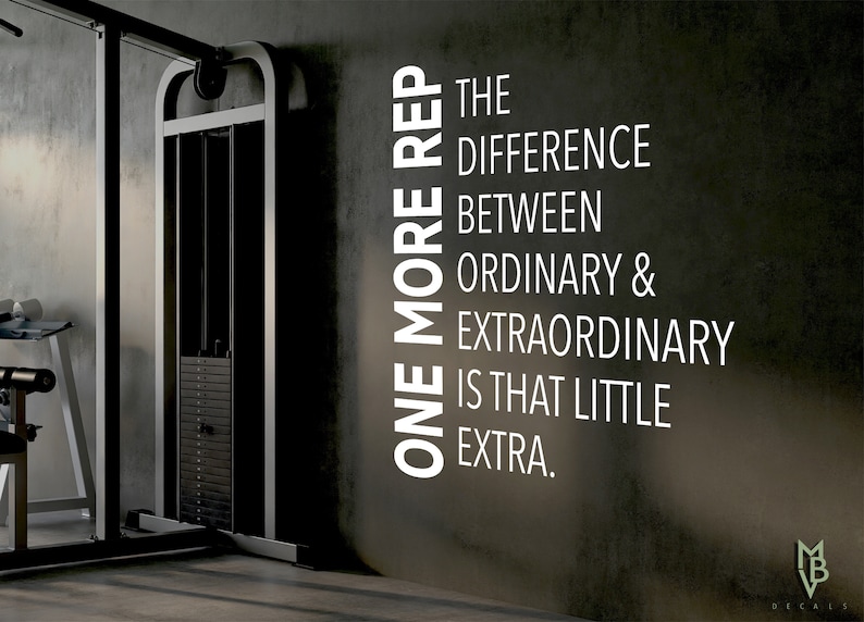 May include: A motivational quote on a gray wall in a gym setting: "One more rep is the difference between ordinary & extraordinary is that little extra."