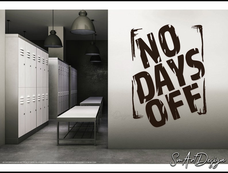 May include: A white wall with a black and white motivational quote that says "NO DAYS OFF" in a bold, stylized font. The quote is framed by a black square with a rough, textured edge. The wall is in a locker room with white lockers and a concrete floor.