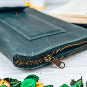 May include: A teal leather zippered wallet with a flap pocket and a brass zipper pull.
