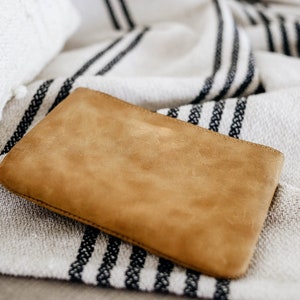 May include: A brown suede clutch purse on a white and black striped throw blanket.