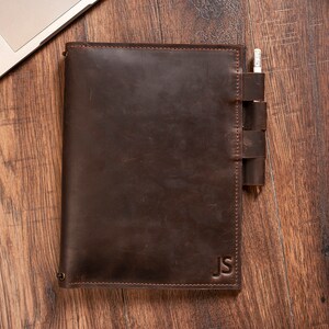 May include: A brown leather notebook with a pen holder and the initials "JS" embossed on the cover.