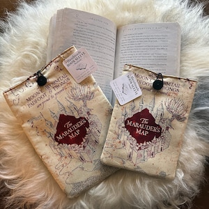 Può includere: Due fodere per libri beige con un designo della mappa dei Dissennatori. Le fodere sono fatte a mano e hanno una chiusura a bottone nero. Il testo sulle fodere recita "Moony, Wormtail, Padfoot & Prongs sono orgogliosi di presentare La Mappa dei Dissennatori".