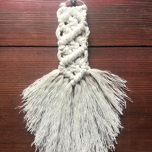 K&ouml;nnte beinhalten: Wei&szlig;er Makramee-Schl&uuml;sselanh&auml;nger mit einem silbernen Schl&uuml;sselring und einer langen Franse.