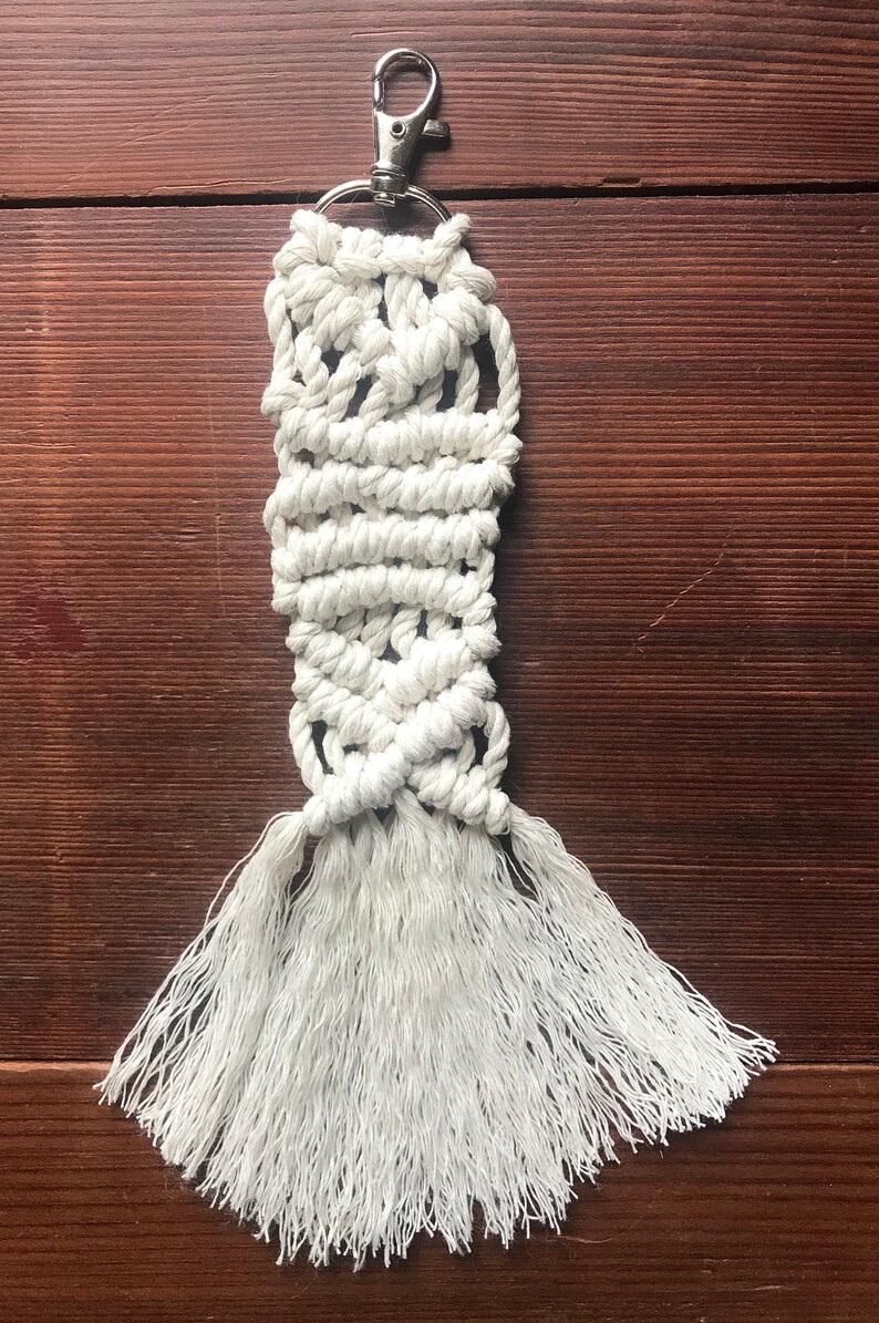 K&ouml;nnte beinhalten: Wei&szlig;er Makramee-Schl&uuml;sselanh&auml;nger mit einem silbernen Schl&uuml;sselring und langen Quasten.