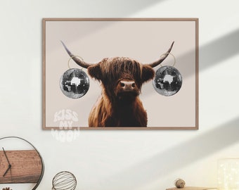 May include: A brown and white Highland cow with disco ball earrings against a light pink background.