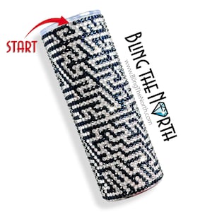 May include: A black and white tumbler with a geometric pattern covered in rhinestones. The tumbler is made of stainless steel and has a clear lid. The text "BLING THE NORTH" is visible on the right side of the image.