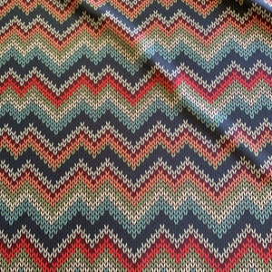Puede incluir: Una tela con un patr&oacute;n de chevron en tonos de rojo, naranja, verde, azul y blanco sobre un fondo azul oscuro.