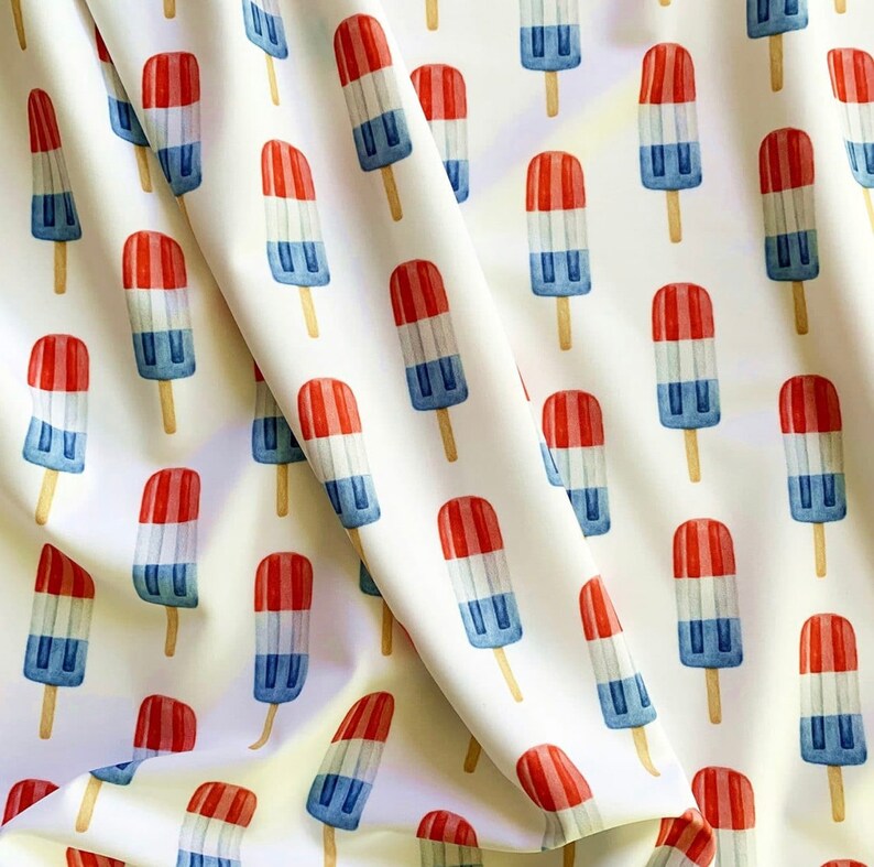 Puede incluir: Tela blanca con un patr&oacute;n repetido de paletas de hielo rojas, blancas y azules. Las paletas de hielo son todas del mismo estilo, con la parte superior roja, la parte media blanca y la parte inferior azul.