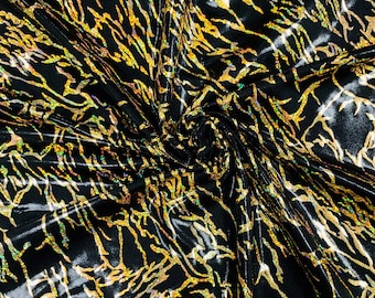 May include: Black fabric with a gold and iridescent swirl pattern. The fabric is shiny and has a textured surface.