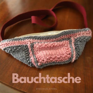 Może przedstawiać: Szara i różowa torba dziana z zamkiem błyskawicznym i burgundowym paskiem. Torba jest oznaczona jako "Bauchtasche", co w języku niemieckim oznacza "torba na brzuch".