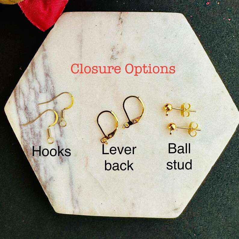 May include: Three types of gold-toned earring findings labeled Closure Options: a pair of wire hooks labeled Hooks, a pair of hinged lever back findings labeled Lever back, and a pair of ball stud posts labeled Ball stud.