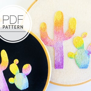 May include: Two embroidery hoops with cactus designs. One hoop has black fabric with a cactus design in yellow, orange, and purple. The other hoop has beige fabric with a similar cactus design. The text "PDF PATTERN" is in a circle.
