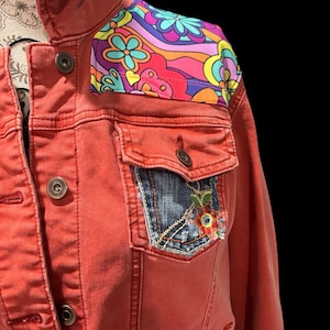 May include: A red denim jacket with a colourful psychedelic pattern on the shoulder and a denim patch on the pocket.