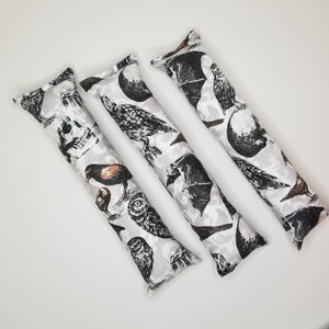May include: Three white catnip kick toys with a black and white print of birds, bats, and skulls.