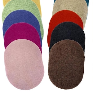 May include: A collection of oval-shaped felt patches arranged in two vertical columns. The colours include light green, yellow, blue, magenta, light pink, beige, red, black, and brown. Each patch features a textured, soft fabric surface.