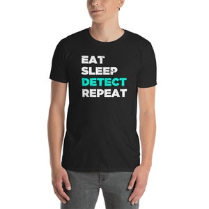 Puede incluir: Camiseta negra con texto blanco que dice "Eat Sleep Detect Repeat" con la palabra "Detect" en turquesa.