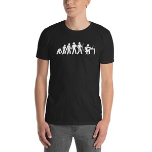 Könnte beinhalten: Schwarzes T-Shirt mit einer weißen Grafik, die die Evolution einer Strichmännchenfigur vom Höhlenmenschen bis zu einer Person zeigt, die an einem Computer sitzt.