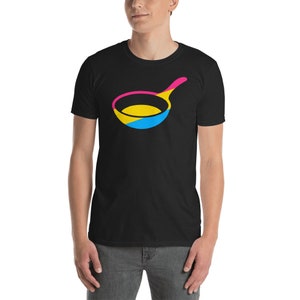 Peut inclure: Un t-shirt noir avec un motif de poêle à frire rose, jaune et bleu. La poêle est stylisée pour ressembler au drapeau de la fierté pansexuelle.