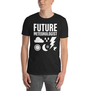 Puede incluir: Camiseta negra con texto blanco que dice "FUTURE METEOROLOGIST" e iconos del tiempo que incluyen una nube, gotas de lluvia, un rayo, un sol, una luna, un copo de nieve y un tornado.