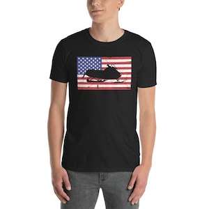 May include: A black t-shirt with a distressed American flag design featuring a silhouette of a snowmobile.