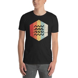 May include: A black t-shirt with a retro-style graphic of a hexagon with different colored stripes and a series of wavy lines inside.