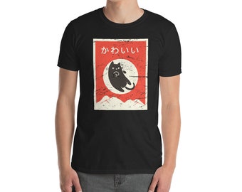 Op de afbeelding: Zwart T-shirt met een vintage-stijl grafische afbeelding van een zwarte kat met het Japanse woord "kawaii" (wat schattig betekent) gedrukt op een rode achtergrond.