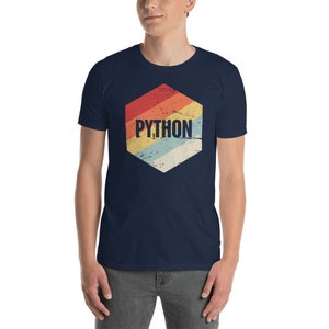 Peut inclure: Un t-shirt bleu marine avec un graphique hexagonal de style r&eacute;tro repr&eacute;sentant le mot "PYTHON" en texte blanc. L'hexagone a un design arc-en-ciel d&eacute;lav&eacute; avec des rayures rouges, orange, jaunes, vertes, bleues et violettes.