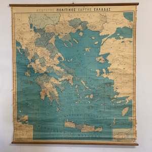 May include: A vintage wall-mounted political map of Greece featuring the text "ΝΕΩΤΑΤΟΣ ΠΟΛΙΤΙΚΟΣ ΧΑΡΤΗΣ ΕΛΛΑΔΑΣ" at the top. The map displays landmasses in beige and water bodies in teal, with wooden dowels at the top and bottom for hanging display.