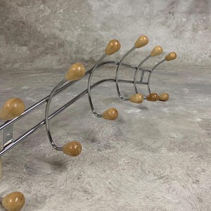 May include: Chrome coat rack with wooden hooks. The rack is curved and has 9 hooks.