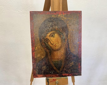 May include: A vintage religious icon painting on wood depicting a woman with dark hair and a blue robe. The painting has a distressed, aged look with cracks in the paint.